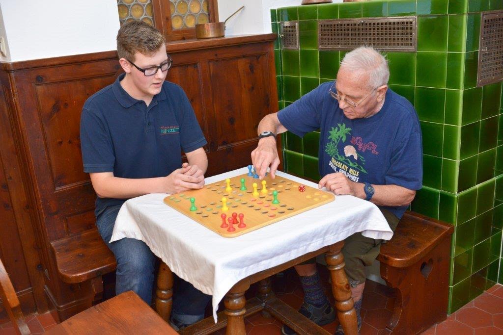 Senior spielt mit Pflegefachkraft in der Tagespflege Brettspiele